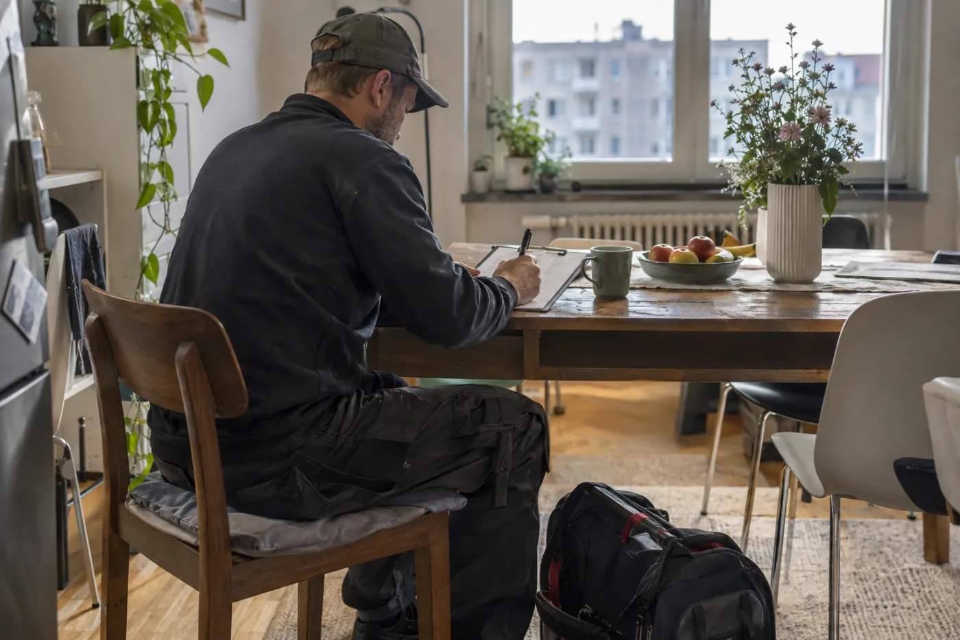 Handwerker hält Notizen auf einem Klemmbrett am Tisch fest.
