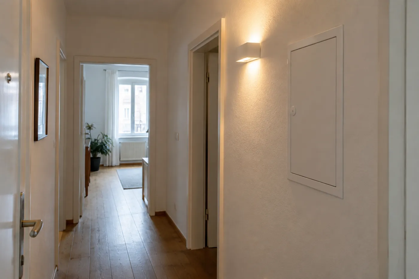 Wohnungsflur mit geschlossenem Verteiler und eingeschalteter Wandleuchte.